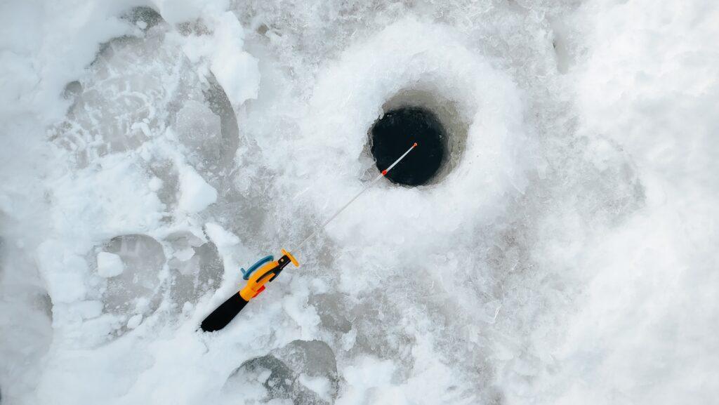 Yellow small fishing rod and a hole in the ice, winter fishing
